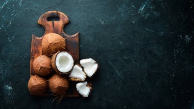 Hindistan cevizi palmiye yaprakları ile siyah bir taş arka plan üzerinde. Tropikal Meyveler. Somun. Üst te. Metniniz için boş alan.