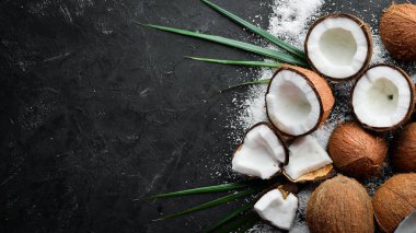 Hindistan cevizi palmiye yaprakları ile siyah bir taş arka plan üzerinde. Tropikal Meyveler. Somun. Üst te. Metniniz için boş alan.