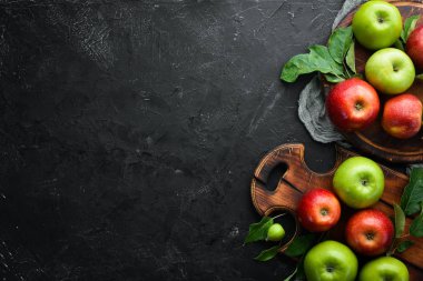 Siyah bir arka plan üzerinde yeşil yaprakları ile renkli elma. Meyve. Üst te. Metin için boş alan.