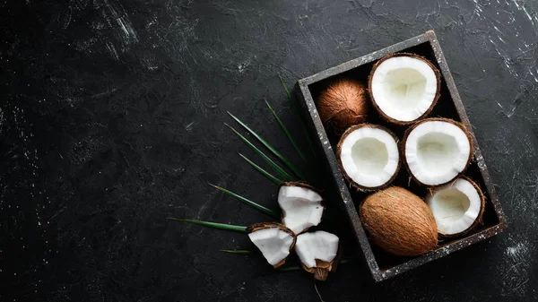 Hindistan cevizi palmiye yaprakları ile siyah bir taş arka plan üzerinde. Tropikal Meyveler. Somun. Üst te. Metniniz için boş alan.