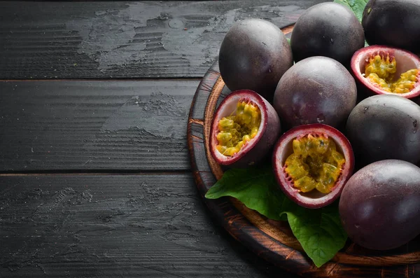 Passion fruits with leaves on a black background. Tropical Fruits. Top view. Free space for text.