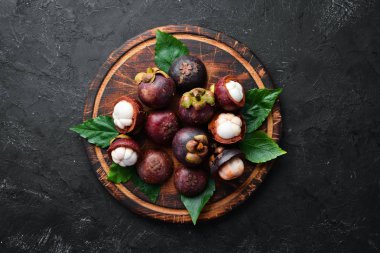 Siyah taş arka plan üzerinde bir yaprak ile Mangosteen. Tropikal Meyveler. Üst te. Metin için boş alan.