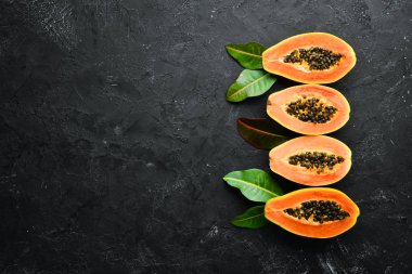 Siyah taş arka plan üzerinde taze papaya. Tropikal Meyveler. Üst te. Metin için boş alan.
