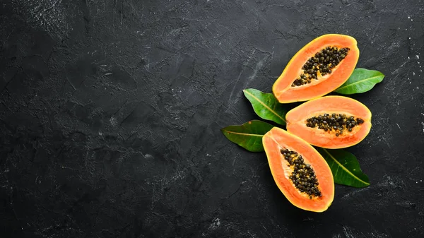 Fresh papaya on a black stone background. Tropical Fruits. Top view. Free space for text.