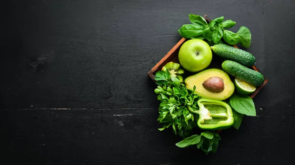 Fresh Green Fruits and Vegetables. Pure selection and source of vegetable protein on a wooden aged background. Avocados, grapes, cucumbers, kiwi, apples, lime, green pepper.