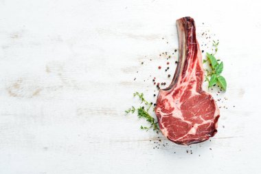 Beyaz ahşap arka planda çiğ kovboy bifteği ve baharatlar. Bbq Top görünümü. Metin için boş alan.