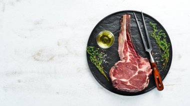 Beyaz ahşap arka planda çiğ kovboy bifteği ve baharatlar. Bbq Top görünümü. Metin için boş alan.