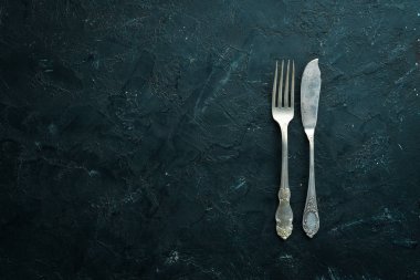 Siyah arka plan üzerinde eski çatal bıçak takımı. Üst te. Metniniz için boş alan.