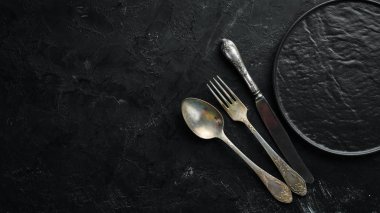 Siyah arka plan üzerinde eski çatal bıçak takımı. Üst te. Metniniz için boş alan.