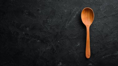 Siyah bir arka plan üzerinde tahta bir kaşık. Üst te. Metniniz için boş alan.