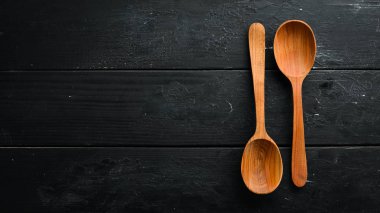Siyah bir arka plan üzerinde tahta bir kaşık. Üst te. Metniniz için boş alan.