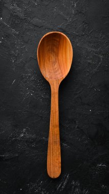 Siyah bir arka plan üzerinde tahta bir kaşık. Üst te. Metniniz için boş alan.