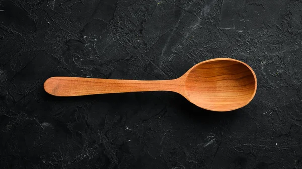 Siyah bir arka plan üzerinde tahta bir kaşık. Üst te. Metniniz için boş alan.