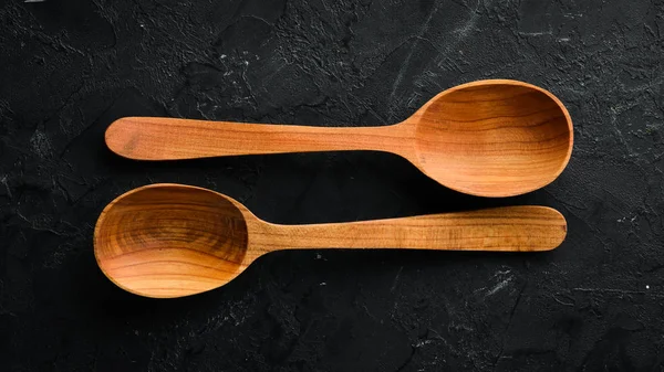 Siyah bir arka plan üzerinde tahta bir kaşık. Üst te. Metniniz için boş alan.
