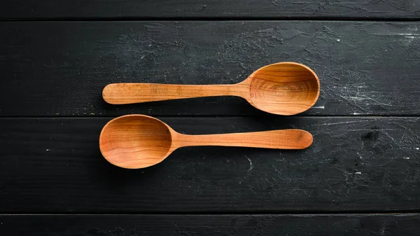 Siyah bir arka plan üzerinde tahta bir kaşık. Üst te. Metniniz için boş alan.