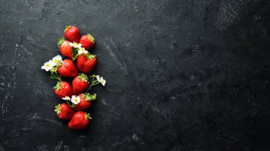 Siyah taş arka plan üzerinde yaprakları ile taze çilek. Çilek Üst görünüm. Metniniz için boş alan.