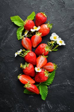 Siyah taş arka plan üzerinde yaprakları ile taze çilek. Çilek Üst görünüm. Metniniz için boş alan.