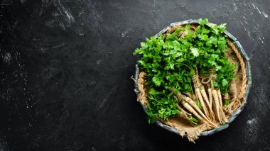 Kök maydanoz ve maydanoz siyah bir arka plan üzerinde. Üst te. Metniniz için boş alan.