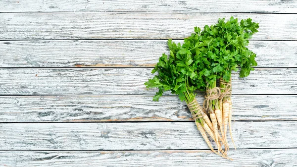 Parsley root on a white wooden background. Top view. Free space for your text.