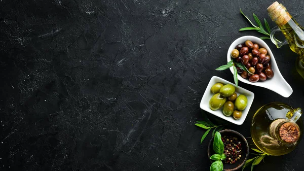 Olives A set of colored olives on a black stone background. Top view. Free space for your text.