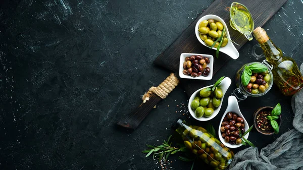 Olives A set of colored olives on a black stone background. Top view. Free space for your text.