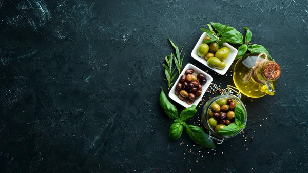 Olives A set of colored olives on a black stone background. Top view. Free space for your text.