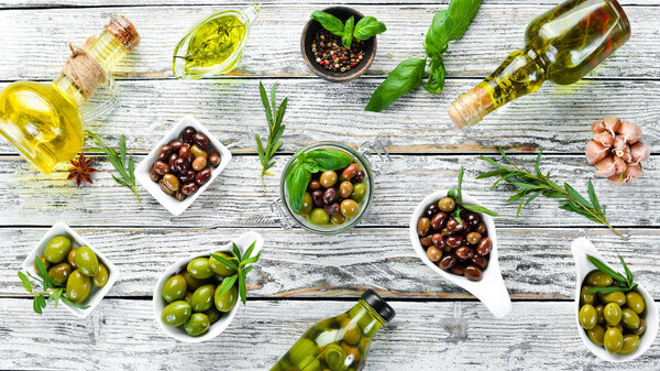 Olive oil and olives on a white wooden background. Top view. Free space for your text.