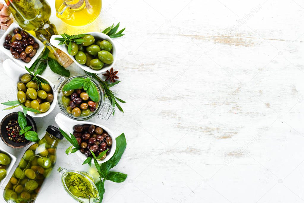 Olive oil and olives on a white wooden background. Top view. Free space for your text.