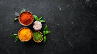 Pişirmek için renkli otlar ve baharatlar. Hint baharatları. Siyah taştan bir arka planda. Üst görünüm.