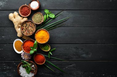Kase ve kaşık büyük baharat ve ot toplama. Hint baharatları. Siyah ahşap bir arka plan üzerinde. Üstte görüntü.