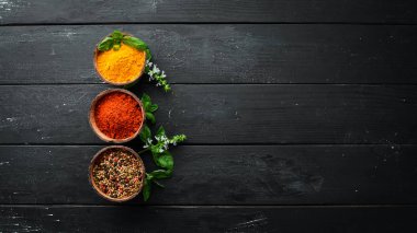 Kase ve kaşık büyük baharat ve ot toplama. Hint baharatları. Siyah ahşap bir arka plan üzerinde. Üstte görüntü.