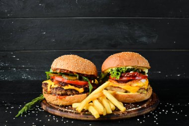 Dana eti, peynir ve sebzeli burger. Fast food. Ahşap bir arka plan üzerinde. Üst te. Metniniz için boş alan.