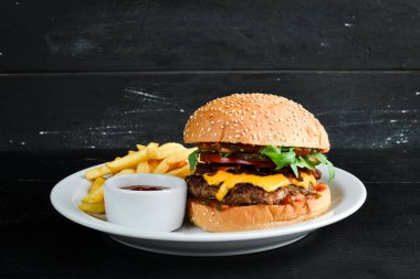Dana eti, peynir ve sebzeli burger. Fast food. Ahşap bir arka plan üzerinde. Üst te. Metniniz için boş alan.
