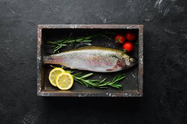 Siyah taş arka planda sebze ile çiğ balık alabalık. Üst te. Metniniz için boş alan.