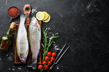 Siyah taş arka planda sebze ile çiğ balık alabalık. Üst te. Metniniz için boş alan.