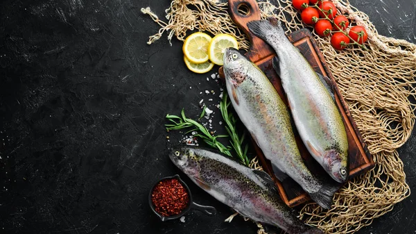 Siyah taş arka planda sebze ile çiğ balık alabalık. Üst te. Metniniz için boş alan.