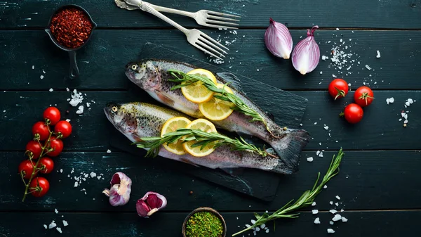 Siyah ahşap arka planda sebze li çiğ balık. Balık alabalığı. Üst te. Metniniz için boş alan.