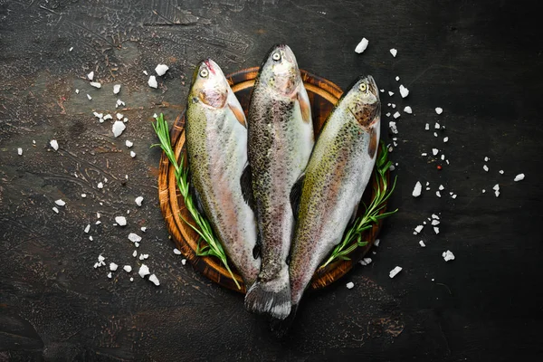 Raw fish with vegetables on a black wooden background. Fish trout. Top view. Free space for your text.