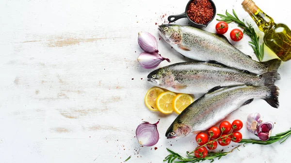 Raw fish with vegetables on a white wooden background. Fish trout. Top view. Free space for your text.