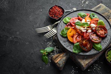 Siyah tabakta caprese salatası. Domates, mozzarella peyniri ve fesleğen. Üst te. Metniniz için boş alan.