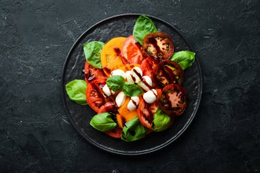 Siyah tabakta caprese salatası. Domates, mozzarella peyniri ve fesleğen. Üst te. Metniniz için boş alan.