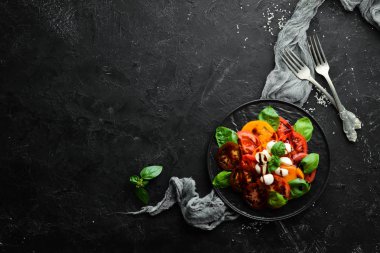Siyah tabakta caprese salatası. Domates, mozzarella peyniri ve fesleğen. Üst te. Metniniz için boş alan.