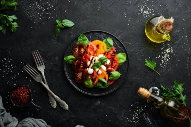 Siyah tabakta caprese salatası. Domates, mozzarella peyniri ve fesleğen. Üst te. Metniniz için boş alan.