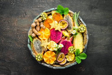 Tropikal meyve - kahverengi bir arka plan üzerinde tutku meyve, ananas, ejderha meyve, kivi ve kaktüs. Üstte görüntü.