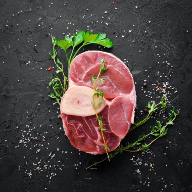 Siyah bir arka plan üzerinde baharat ve otlar ile Osso Buco yapmak için Ham taze çapraz kesilmiş dana sapı. Üst te. Metniniz için boş alan.