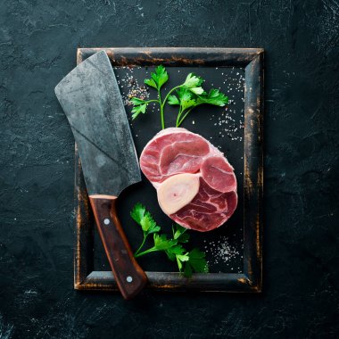 Siyah bir arka plan üzerinde baharat ve otlar ile Osso Buco yapmak için Ham taze çapraz kesilmiş dana sapı. Üst te. Metniniz için boş alan.