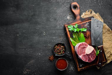 Siyah bir arka plan üzerinde baharat ve otlar ile Osso Buco yapmak için Ham taze çapraz kesilmiş dana sapı. Üst te. Metniniz için boş alan.