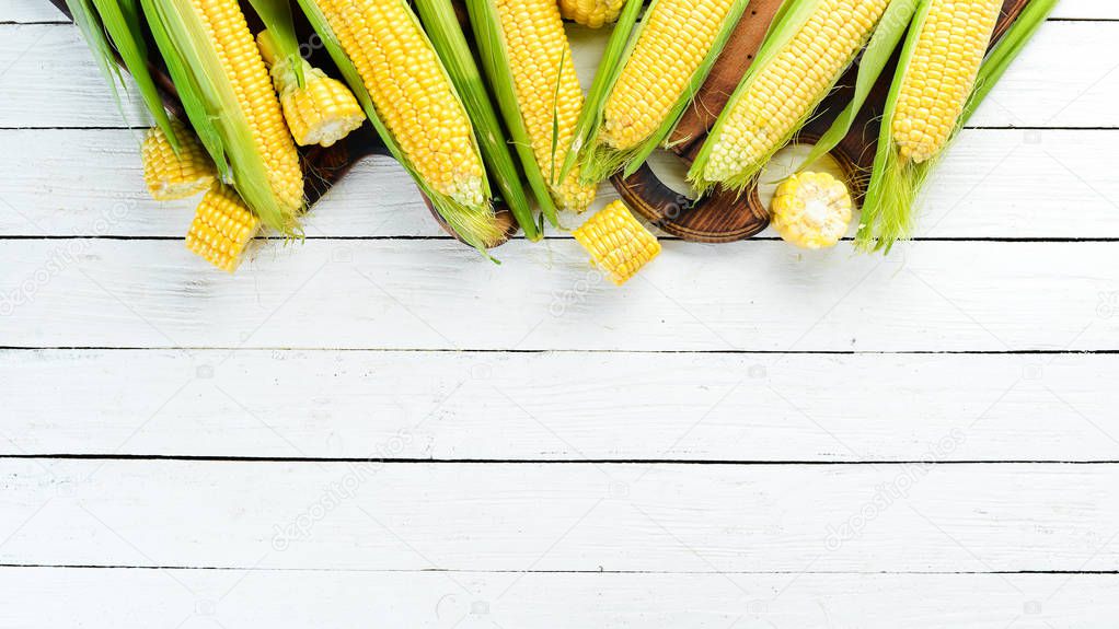 Fresh yellow corn on a white wooden background. Vegetables. Top view. Free copy space.
