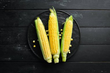 Siyah bir arka planda taze mısır. Sebze. Üst görünüm. Ücretsiz kopya alanı.