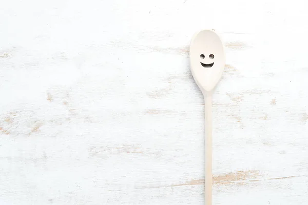 A wooden spoon on a white wooden background. Top view. Free copy space.